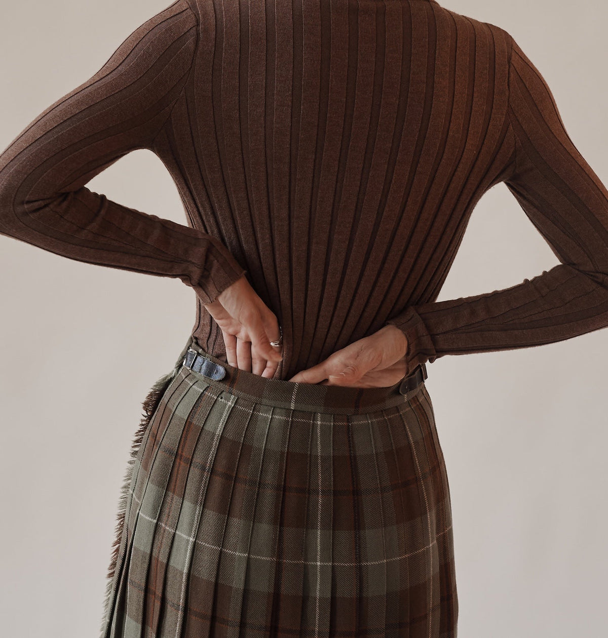 a women in pleated skirt with her hands behind her back